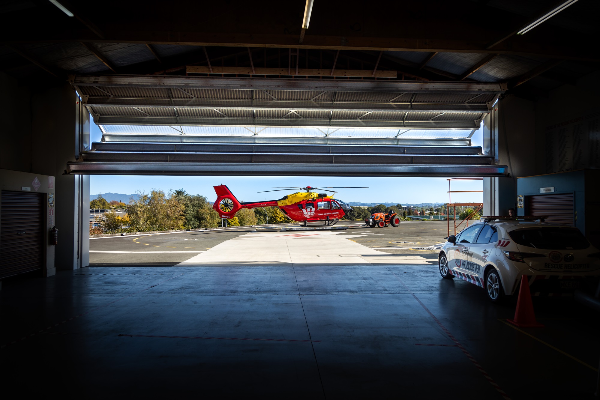 Bifold hangar door opening to reveal Waikato Westpac Helicopter